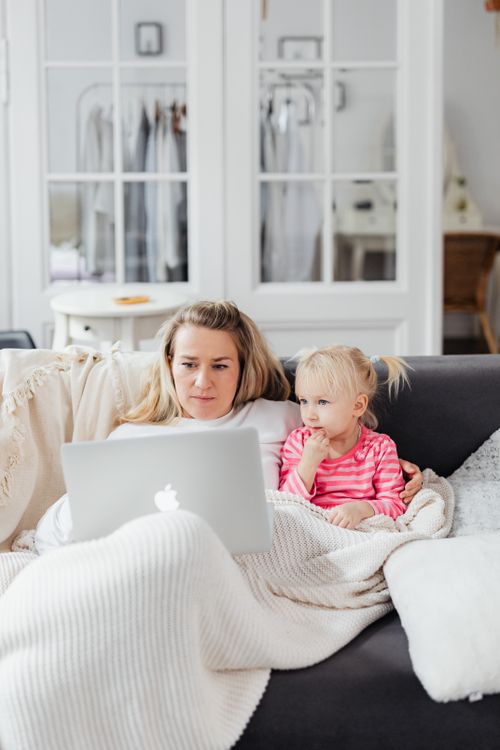 Free A mother and daughter cozy up on the sofa, sharing a laptop in a home setting, enjoying quality bonding time. Stock Photo