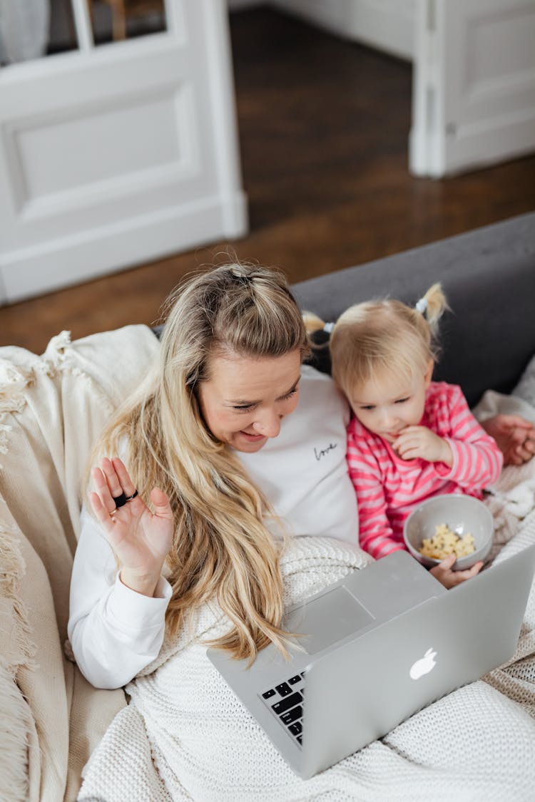 Blonde Girl Eating Popcorn Beside The Woman With A Laptop