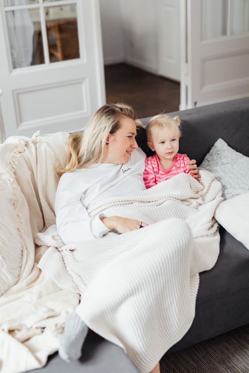 Free A mother and daughter enjoying bonding time wrapped in a blanket on a cozy couch. Stock Photo