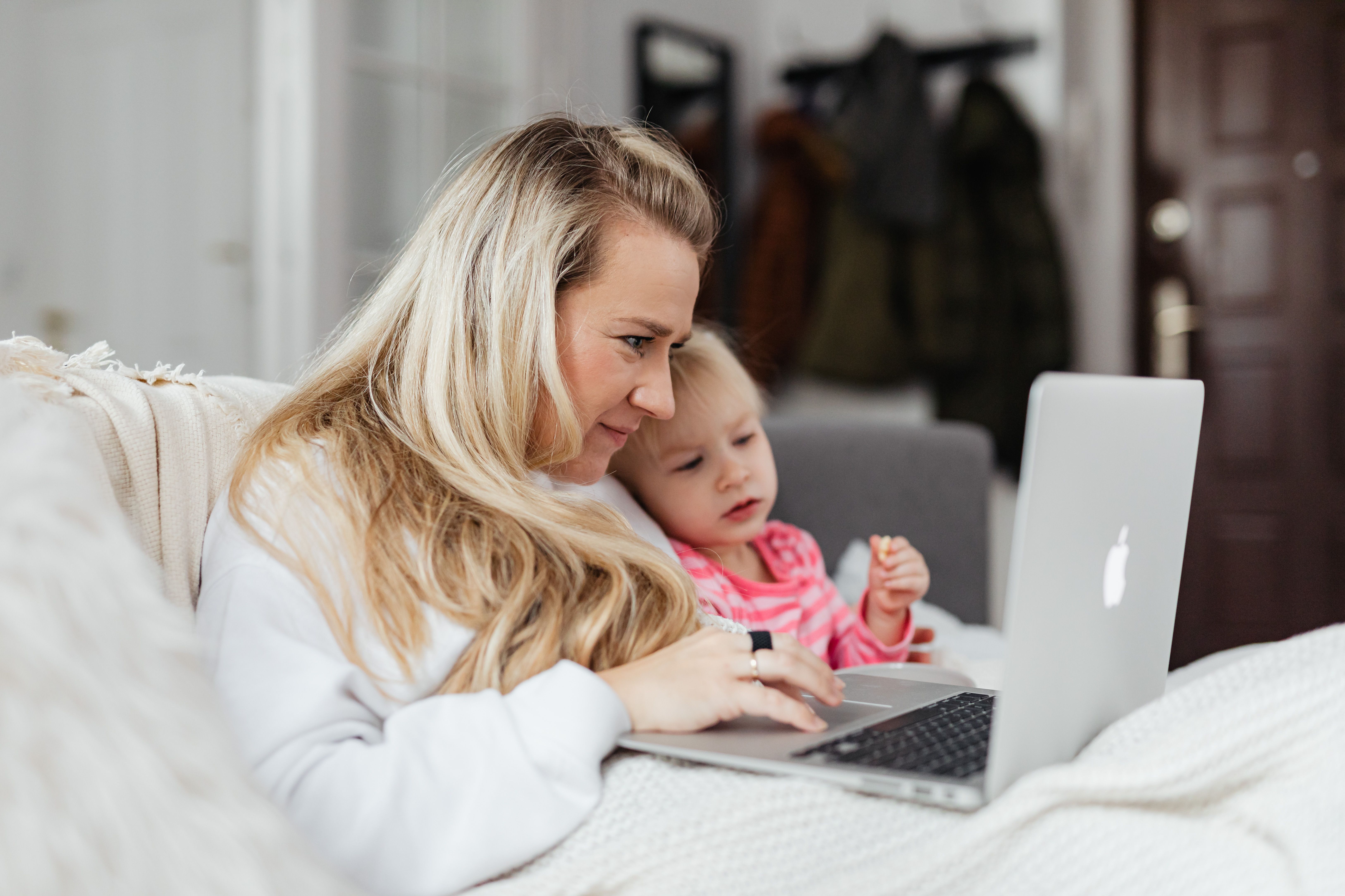 A mother and her daughter enjoy quality time together using a laptop indoors.