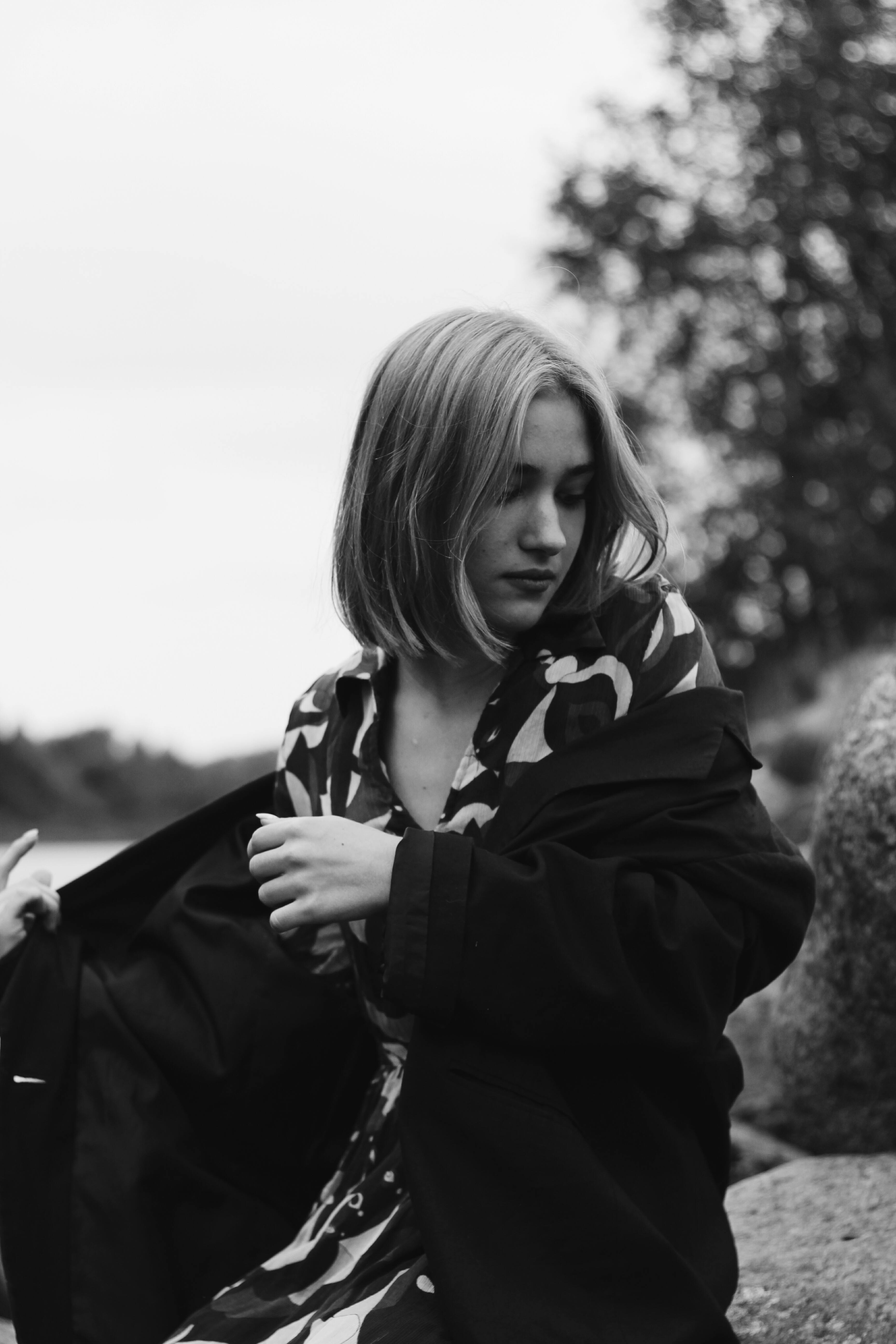 Elegant black and white portrait of a woman in stylish attire outdoors.