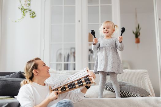 Mother and Little Daughter Holding Rattles and Chromatic Bells 