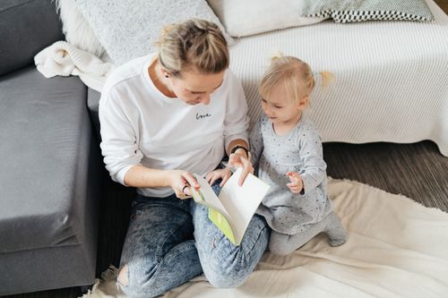 Free Mother and daughter bonding over a book in a cozy living room setting. Stock Photo