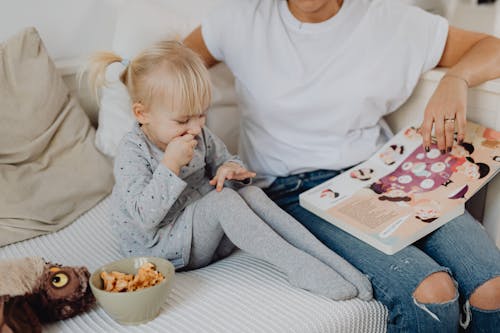 A Kid Eating Cookies While Listening To Mom's Book Reading