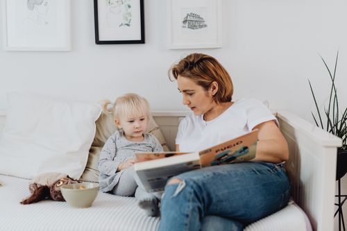 Free A mother and child share a quiet moment reading a book on a cozy couch. Perfect for family and lifestyle themes. Stock Photo