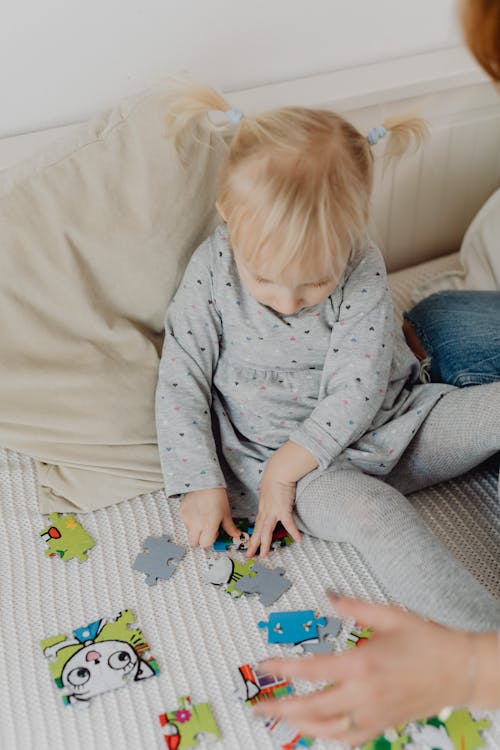 A Girl Playing a Puzzle Toy on the Bed