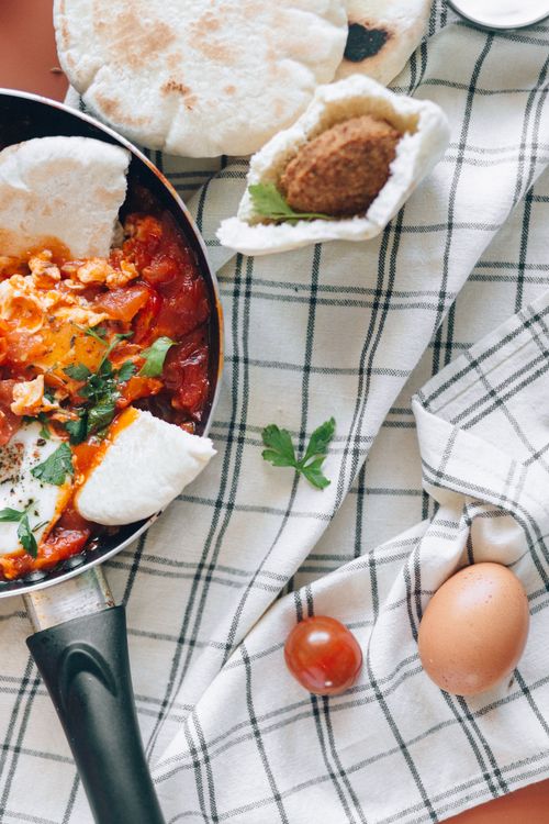 Free A vibrant shakshuka dish with pita bread and falafel, perfect for a flavorful brunch. Stock Photo