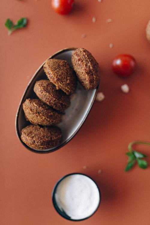 Free High angle view of falafel served with cherry tomatoes and sauce on a warm orange surface. Stock Photo