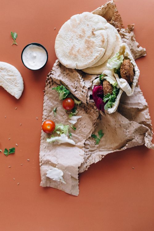 Free High angle view of falafel wraps with cherry tomatoes and sauce on paper. Stock Photo
