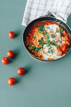 Delicious pan of homemade shakshuka garnished with herbs and cherry tomatoes.