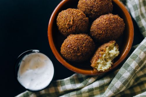 Free Close-up shot of crispy falafel balls served with creamy tahini sauce in an inviting setting. Stock Photo