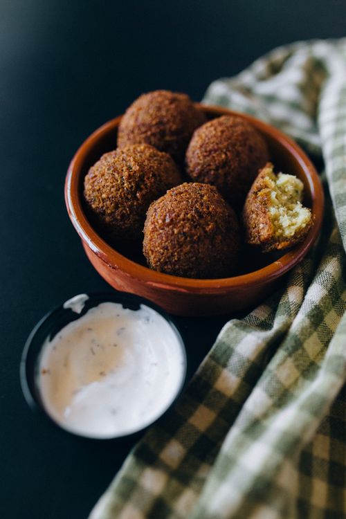 Free Delicious falafel in a ceramic bowl with creamy dip on the side, perfect for food photography. Stock Photo