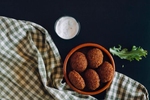Free Crispy falafel served with yogurt dip and lettuce leaves on a checkered cloth flat lay. Stock Photo