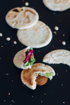 A close-up shot of savory falafel wraps with fresh fillings on a dark background.