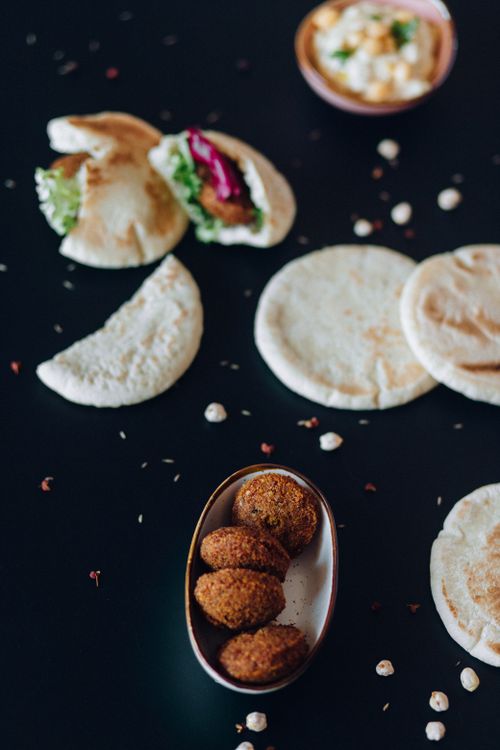 Free A visually appetizing display of falafel, pita, and hummus on a black surface. Stock Photo