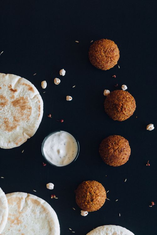 Free Falafel balls with pita bread and sauce on a black surface, perfect for food photography. Stock Photo