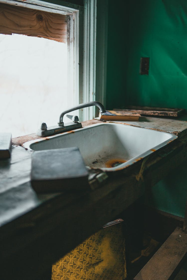 Sink With Rust Against Window In Old House