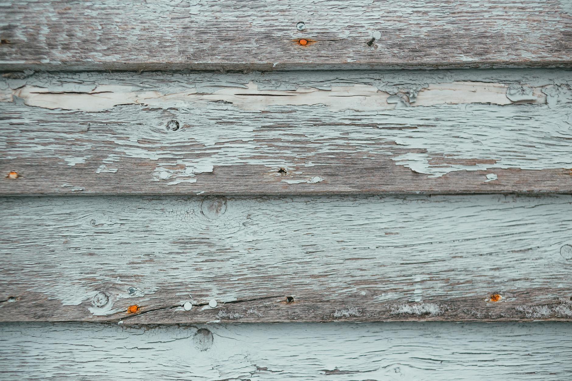 Close-up of rustic wooden planks with peeling paint, showcasing texture and weathered surfaces.