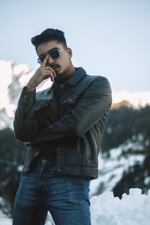Photo of a Man in a Black Leather Jacket Touching His Sunglasses