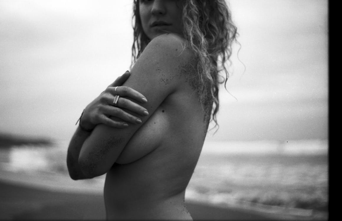 Black and White Photo of a Topless Woman Touching Her Arm