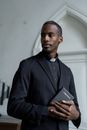 Man in Black Suit Holding a Black Book