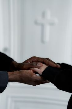 An intimate moment showing hands holding in front of a cross, symbolizing support and connection.