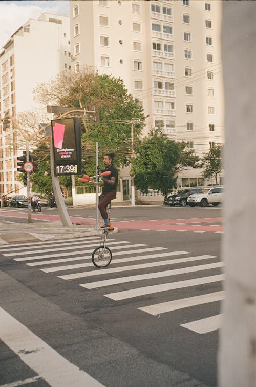 A Man Riding a Unicycle while Holding Juggling Clubs