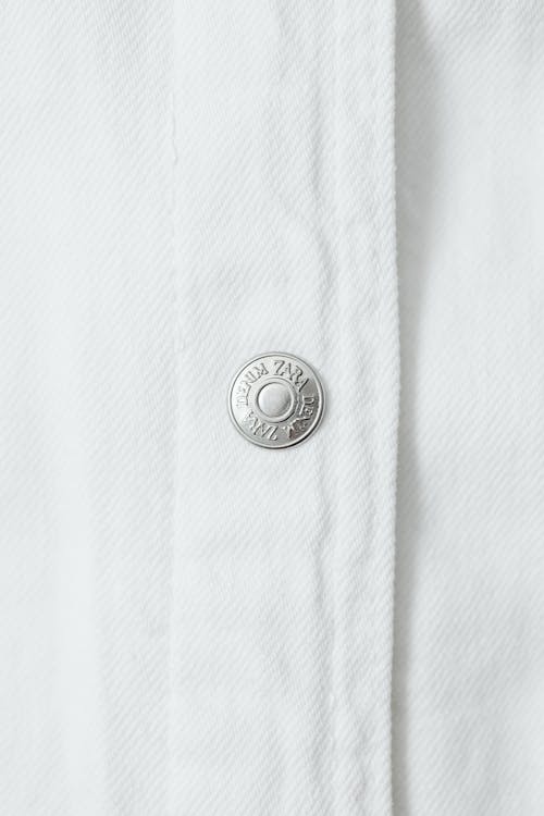 Free Close-Up Photo of a Silver Button on a White Textile Stock Photo