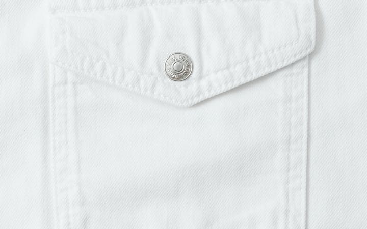 Detailed close-up of a white cotton shirt pocket with button.