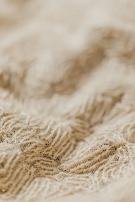 Gros plan sur les fibres d'un tissu en maille écru, la matière qui décide entre sublimation et transfert DTF
