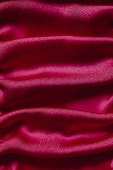 High-quality close-up of red satin fabric with smooth, shiny folds.