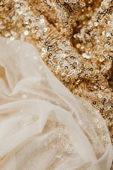 Close-up of elegant gold sequin fabric intertwined with delicate sheer tulle.