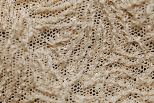 Close-up view of intricately woven beige lace fabric showcasing texture and pattern.
