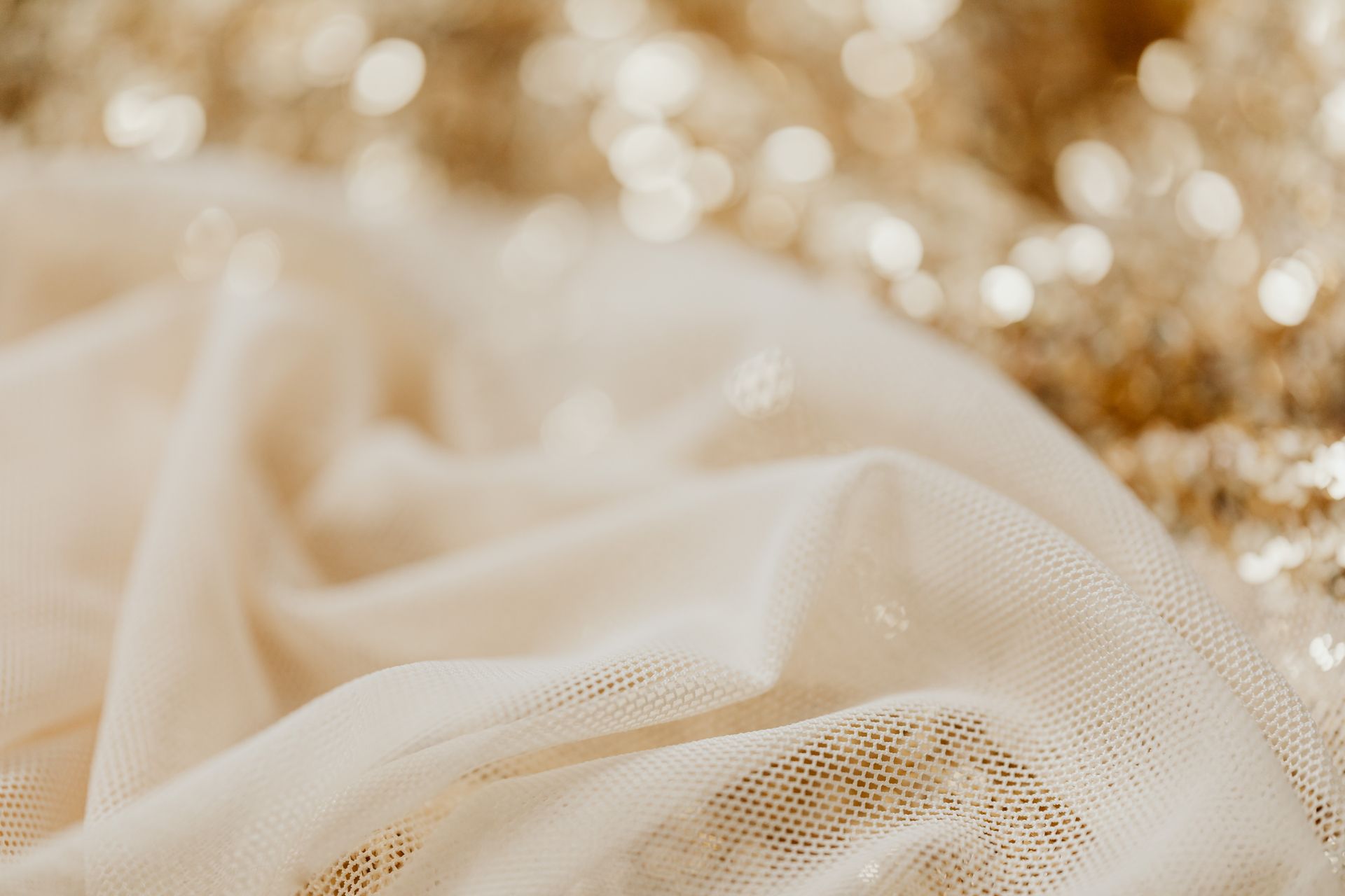 Elegant close-up of mesh fabric with a golden bokeh background creates a soft and luxurious texture.