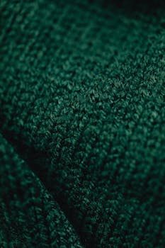 Detailed macro shot of a green textured textile surface, showcasing intricate patterns and rich color.