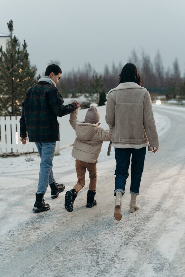 A Family Walking On A Snowy Road