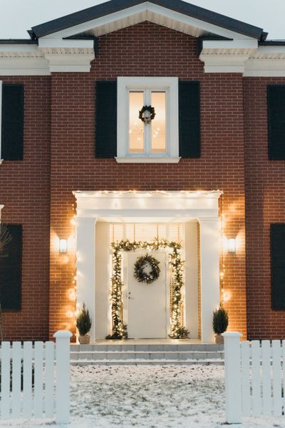 Holiday entrance inspiration with warm white lights, garland, and a wreath