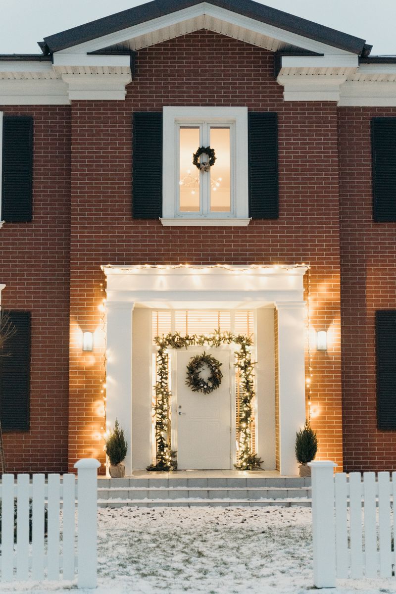 Christmas entrance inspiration with a wreath, garland, and warm white lights around a front door