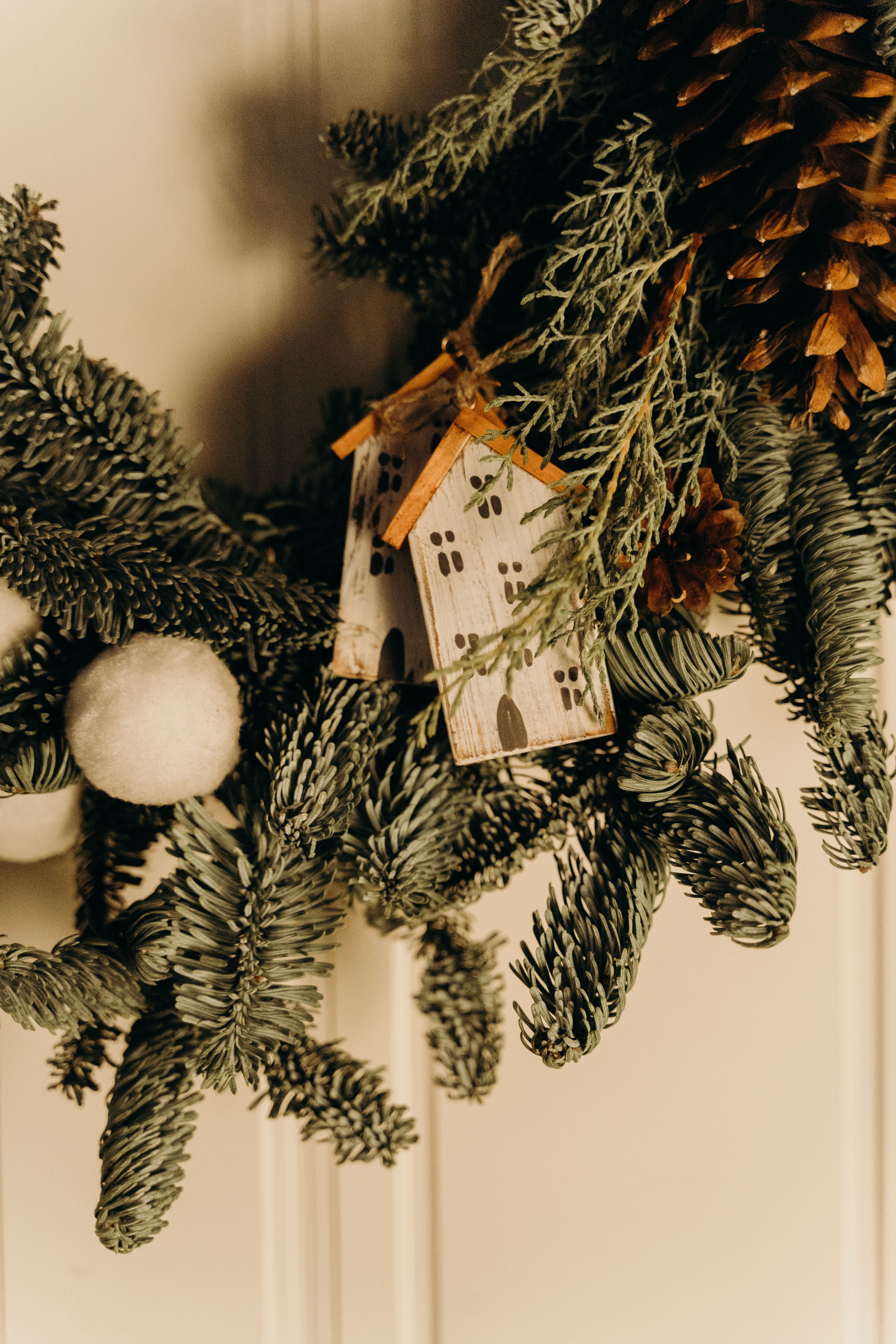 Free Festive wreath with pinecones and decorative mini houses for a cozy Christmas touch. Stock Photo