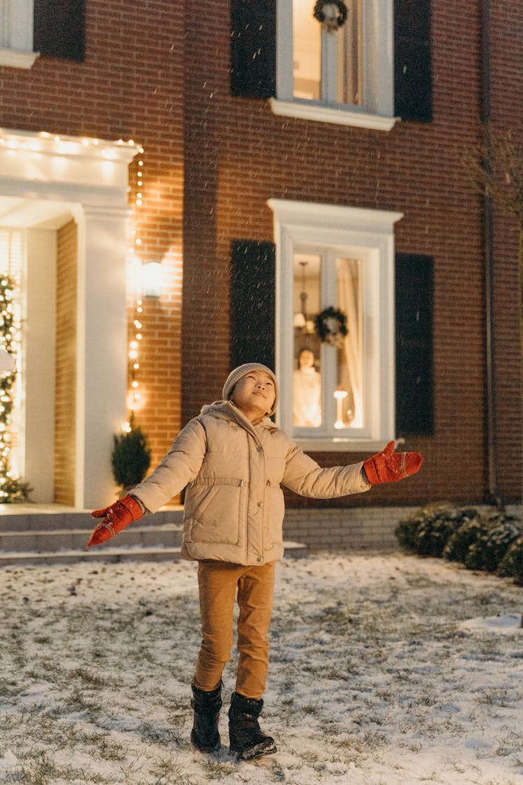 A Kid In Winter Clothes Enjoying The Snow Outside