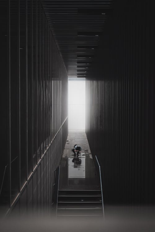 Black and White Photo of a Narrow Tunnel and Escalator Going Down 