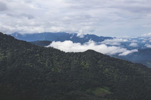 Free A breathtaking view of lush green mountains with rolling clouds and a vast sky. Stock Photo