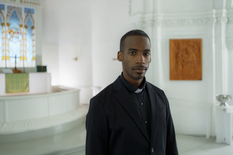 Photograph Of A Pastor In Black Clothes Looking At The Camera