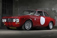 一辆令人惊叹的复古红色老爷车停在工业风格的室内背景中，展现出优雅与设计感