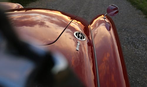 Red Vehicle With Wing Mirror on Its Hood Outdoors during Day