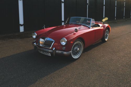 Free Vintage red convertible car gleaming on a street with sunlight creating a nostalgic feel. Stock Photo