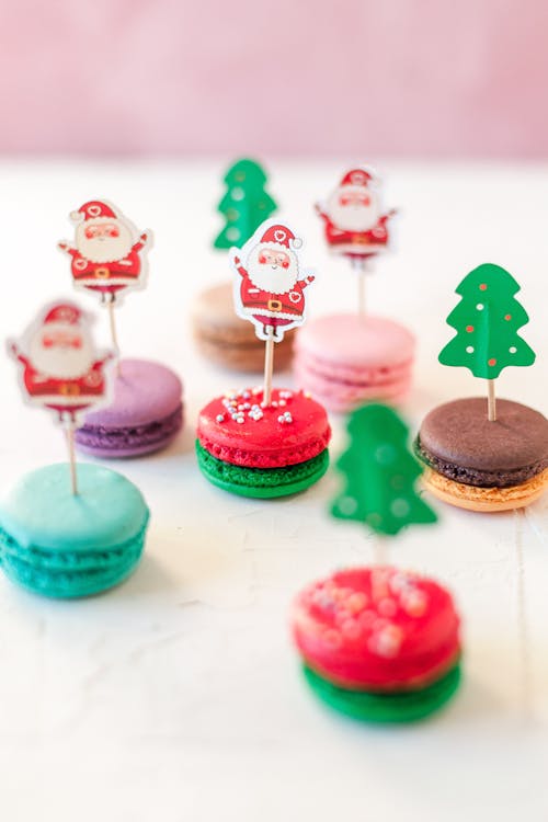 Delicious multicolored macaroons decorated with Santa Clauses and Christmas Tree figures arranged on white table
