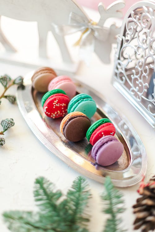 Composition of colorful palatable macaroons served on steel tray on white table in light room