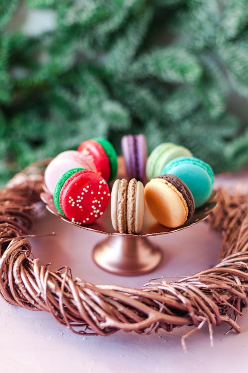 Free Sweet colorful macaroons served on bowl on white table near wooden wreath in living room Stock Photo