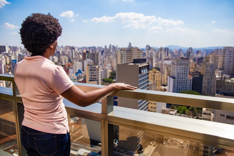 Woman Standing On Balcony Overlooking City